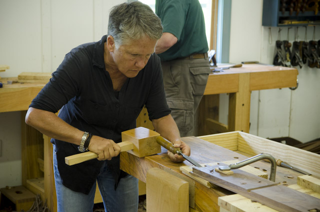 An older female student using a joiner's mallet to hit a chisel while making dovetails