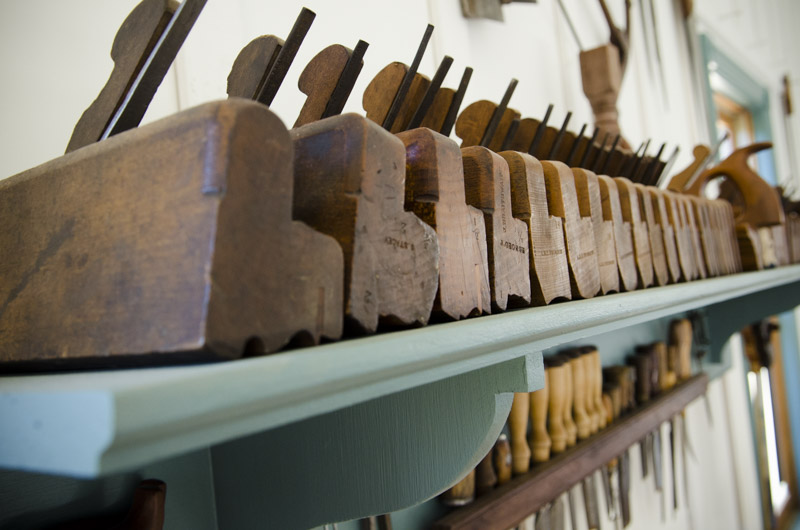 Antique moulding planes (molding planes) lined up on a shelf in Joshua Farnsworth's Wood And Shop Traditional Woodworking School
