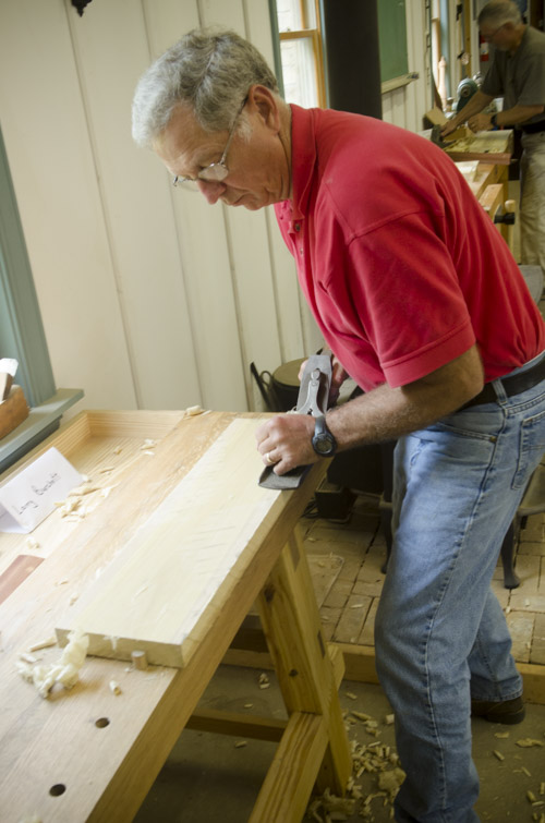 male woodworking student using a stanley bailey No. 7 jointer plane to flatten the face of a poplar board on a woodworking workbench at Joshua Farnsworth's Wood And Shop Woodworking School