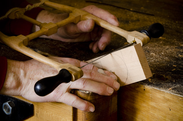Bill Anderson using a small bow saw to cut out a handplane wedge while making a wooden bench plane